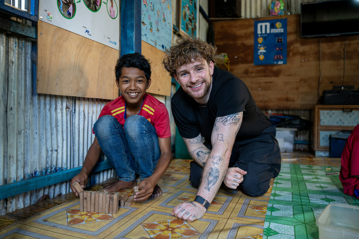 A child, Roun-Ry and Tom Grennan sit smiling toward the camera.